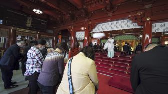 Seorang pendeta berdoa untuk jamaah pada hari pertama kerja di tahun baru di kuil Kanda Myojin, Tokyo, Senin (4/1/2021). [Kazuhiro NOGI / AFP]