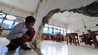 Seorang murid mengintip adik kelasnya yang sedang mengikuti kegiatan belajar mengajar di SDN 226/III Renah Kasah, Kerinci, Jambi, Senin (4/1/2021). [ANTARA FOTO/Wahdi Septiawan]