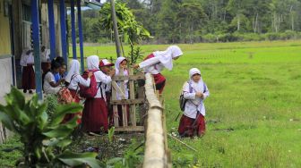 Sejumlah murid melompati pagar usai mengikuti kegiatan belajar mengajar di halaman SDN 226/III Renah Kasah, Kerinci, Jambi, Senin (4/1/2021). [ANTARA FOTO/Wahdi Septiawan]