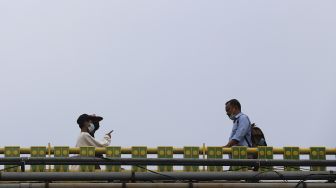 Pekerja berjalan di kawasan Dukuh Atas, Jakarta, Rabu (6/1/2021). [Suara.com/Angga Budhiyanto]