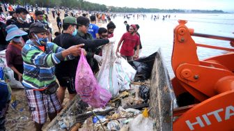 Relawan membersihkan sampah yang berserakan saat mengikuti aksi bersih sampah di Pantai Kuta, Badung, Bali, Rabu (6/1/2021). ANTARA FOTO/Fikri Yusuf