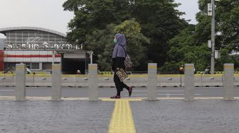 Pekerja berjalan di kawasan Dukuh Atas, Jakarta, Rabu (6/1/2021). [Suara.com/Angga Budhiyanto]