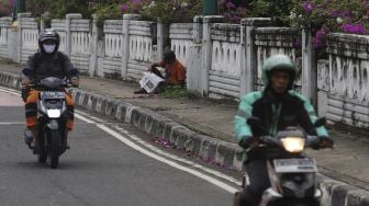 Penyandang Masalah Kesejahteraan Sosial (PMKS) membaca koran di kawasan Kuningan, Jakarta, Kamis (7/1/2021). [Suara.com/Angga Budhiyanto]