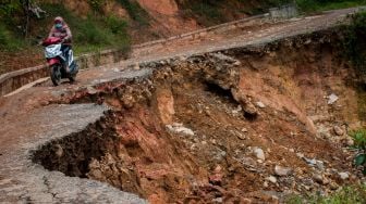 Warga menggunakan kendaraan roda dua melintas di jalan yang longsor di Desa Citorek Kidul, Lebak, Banten, Jumat (8/1/2021).  ANTARA FOTO/Muhammad Bagus Khoirunas