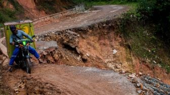 Warga menggunakan kendaraan roda dua melintas di jalan yang longsor di Desa Citorek Kidul, Lebak, Banten, Jumat (8/1/2021).  ANTARA FOTO/Muhammad Bagus Khoirunas