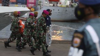 Prajurit TNI Angkatan Darat membawa kantong jenazah berisi bagian tubuh korban dan serpihan pesawat Sriwijaya Air SJ 182 rute Jakarta - Pontianak yang hilang kontak di perairan Kepulauan Seribu, di Dermaga JICT, Tanjung Priok, Jakarta, Senin (11/1/2021). [Suara.com/Angga Budhiyanto]