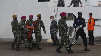 Prajurit TNI Angkatan Darat membawa kantong jenazah berisi bagian tubuh korban dan serpihan pesawat Sriwijaya Air SJ 182 rute Jakarta - Pontianak yang hilang kontak di perairan Kepulauan Seribu, di Dermaga JICT, Tanjung Priok, Jakarta, Senin (11/1/2021). [Suara.com/Angga Budhiyanto]