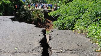 Sejumlah warga menyaksikan lokasi tanah longsor di jalan raya Wonosobo-Kebumen Desa Trimulyo, Wadaslintang, Wonosobo, Jawa Tengah, Selasa (12/1/2021). [ANTARA FOTO/Anis Efizudin]
