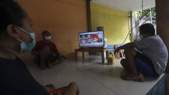 Warga menonton televisi yang menayangkan langsung penyuntikan vaksin CoronaVac perdana di Jakarta, Rabu (13/1/2021). [Suara.com/Angga Budhiyanto]