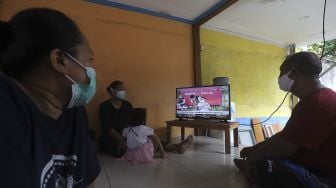 Warga menonton televisi yang menayangkan langsung penyuntikan vaksin CoronaVac perdana di Jakarta, Rabu (13/1/2021). [Suara.com/Angga Budhiyanto]