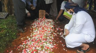 Kerabat dan keluarga berdoa diatas pusara Syekh Ali Jaber setelah dimakamkan di Pesantren Daarul Quran, Tangerang, Banten, Kamis (14/1/2021). [Suara.com/Alfian Winanto]