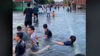 Bak Wahana Wisata, Warga Santai Main Air di Ruas Jalan yang Banjir