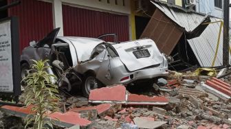 Sebuah mobil dan bangunan rusak akibat gempa bumi, di Mamuju, Sulawesi Barat, Jumat (15/1/2021). [ANTARA FOTO/Akbar Tado]