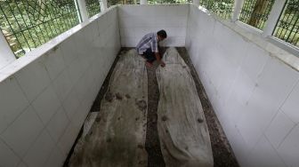 Pekerja membersihkan makam pahlawan nasional Panglima Polem di Desa Lamsie, Aceh Besar, Aceh, Minggu (17/1/2021).  [ANTARA FOTO/Irwansyah Putra]