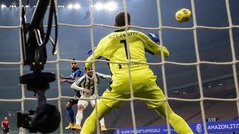 Gelandang Inter Milan Arturo Vidal menyundul bola  melewati kiper Juventus Wojciech Szczesny selama pertandingan sepak bola Serie A Italia Inter melawan Juventus  di Stadion Guiseppe Meazza, Senin (18/1/2021) dini hari WIB. Miguel MEDINA / AFP