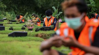 Sejumlah pelanggar protokol kesehatan COVID-19 berdoa saat penerapan sanksi di TPU Jombang, Kota Tangerang Selatan, Banten, Senin (18/1/2021).  ANTARA FOTO/Fauzan
