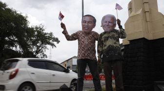 Warga menggunakan topeng berwajah presiden RI Joko Widodo (kiri) dan presiden Amerika Serikat terpilih Joe Biden (kanan) berjalan bersama saat aksi di Jalan Jendral Sudirman, Solo, Jawa Tengah, Rabu (20/1/2021).  ANTARA FOTO/Maulana Surya

