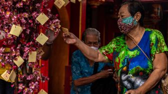 Warga lanjut usia (lansia) memilih kertas pada pohon doa dan harapan usai menerima angpau dari Yayasan Kelenteng Tay Kak Sie di Semarang, Jawa Tengah, Jumat (22/1/2021).  [ANTARA FOTO/Aji Styawan]

