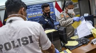 Polisi merapikan barang bukti kasus pemalsuan surat keterangan hasil tes swab saat rilis di Ditreskrimum Polda Metro Jaya, Jakarta, Senin (25/1/2021).[ANTARA FOTO/M Risyal Hidayat]