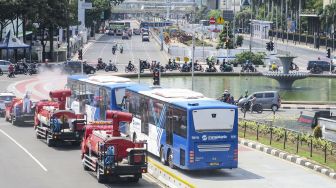 Petugas dari Badan Intelijen Negara (BIN) melakukan penyemprotan cairan disinfektan ke arah sepeda sewa yang berada di Jalan Medan Merdeka Timur, Jakarta, Senin (25/1/2021). ANTARA FOTO/M Risyal Hidayat