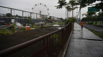 Warga berjalan di samping kawasan Suroboyo Carnival Park yang telah dibongkar di Surabaya, Jawa Timur, Senin (25/1/2021). [ANTARA FOTO/Zabur Karuru]