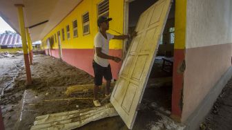 Warga melihat kondisi sebuah bangunan sekolah dasar negeri yang terdampak banjir bandang di Desa Datar Ajab, Kabupaten Hulu Sungai Tengah, Kalimantan Selatan, Minggu (24/1/2021). [ANTARA FOTO/Bayu Pratama S]