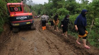 Sejumlah warga melintasi jalan yang tertutup tanah longsor di lereng Gunung Merapi, Cluntang, Musuk, Boyolali, Jawa Tengah, Selasa (26/1/2021). [ANTARA FOTO/Aloysius Jarot Nugroho]