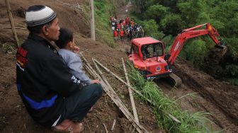 Warga melihat petugas Badan Penanggulangan Bencana Daerah (BPBD) Kabupaten Boyolali menggunakan alat berat saat membuka akses jalan yang tertutup tanah longsor di lereng Gunung Merapi, Cluntang, Musuk, Boyolali, Jawa Tengah, Selasa (26/1/2021). [ANTARA FOTO/Aloysius Jarot Nugroho]