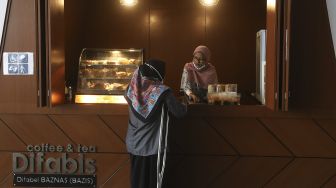 Pedagang disabilitas menunggu pembeli di kedai Difabis Coffee & Tea, kawasan Terowongan Kendal, Jakarta Pusat, Selasa (26/1/2021). [Suara.com/Angga Budhiyanto]