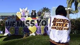 Sejumlah penggemar berkumpul di dekat sebuah poster dari mendiang pemain bola basket profesional NBA Kobe Bryant dan mendiang putrinya Gianna di pusat Kota Los Angeles, California, Amerika Serikat, Selasa (26/1/2021).  [Frederic J. BROWN / AFP]
