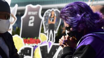 Sejumlah penggemar berkumpul di dekat sebuah poster dari mendiang pemain bola basket profesional NBA Kobe Bryant dan mendiang putrinya Gianna di pusat Kota Los Angeles, California, Amerika Serikat, Selasa (26/1/2021).  [Frederic J. BROWN / AFP]
