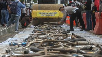 Petugas Kepolisian Satlantas Polrestabes Medan menggunakan alat berat disaat memusnahkan barang bukti tangkapan knalpot brong (bising) di Medan, Sumatera Utara, Kamis (28/1/2021). ANTARA FOTO/Rony Muharrma