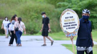 Petugas mensosialisasikan penerapan protokol kesehatan bagi wisatawan di kawasan Garuda Wisnu Kencana (GWK) Cultural Park di Badung, Bali, Sabtu (30/1/2021). [ANTARA FOTO/Fikri Yusuf]