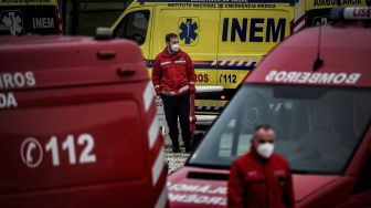 Petugas pemadam kebakaran berdiri di tengah lusinan ambulans yang menunggu di luar layanan darurat COVID-19 di Rumah Sakit Santa Maria, Lisbon, pada (28/1/2021). [PATRICIA DE MELO MOREIRA / AFP]