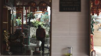 Refleksi pekerja membersihkan area Vihara Amurva Bhumi (Hok Tek Tjeng Sin) menjelang Tahun Baru China atau Imlek di Kelurahan Karet Semanggi, Jakarta, Sabtu (30/1/2021). [Suara.com/Angga Budhiyanto]