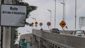 Warga melintasi Flyover Lenteng Agung di Jakarta Selatan, Minggu (31/1/2021). [Suara.com/Alfian Winanto]