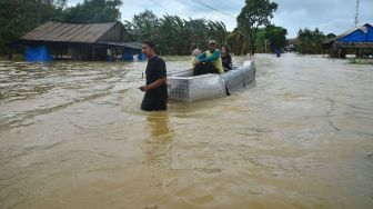 Warga menggunakan perahu melintasi jalan yang terendam banjir di Desa Kedungdowo, Kudus, Jawa Tengah, Selasa (2/2/2021). [ANTARA FOTO/Yusuf Nugroho]
