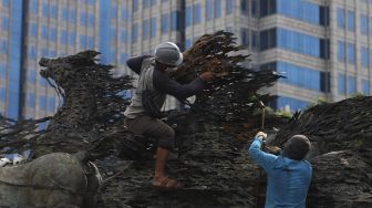 Pekerja melakukan perawatan patung Asta Brata (Arjuna Wijaya) di jalan Medan Merdeka Barat, Jakarta, Selasa (2/2/2021). [Suara.com/Angga Budhiyanto]