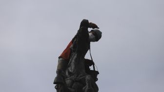 Pekerja melakukan perawatan patung Asta Brata (Arjuna Wijaya) di jalan Medan Merdeka Barat, Jakarta, Selasa (2/2/2021). [Suara.com/Angga Budhiyanto]