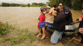 Warga mengevakuasi wanita lanjut usia saat banjir menggenangi Dusun Manisrenggo, Desa Gondangmanis, Kecamatan Bandar Kedungmulyo, Kabupaten Jombang, Jawa Timur, Jumat (5/2/2021). ANTARA FOTO/Syaiful Arif