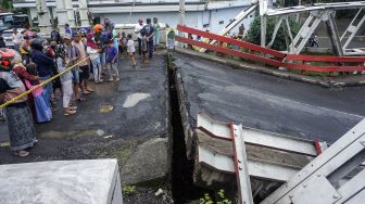 Warga melihat jembatan perbatasan yang ambles di Kabupaten Pekalongan, Jawa Tengah, Jumat (5/2/2021). ANTARA FOTO/Harviyan Perdana Putra
