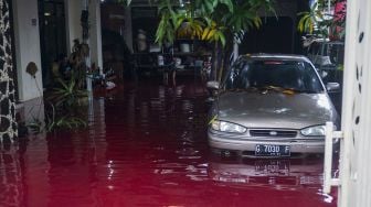 Warga mengamati rumahnya yang tergenang banjir berwarna merah di Jenggot, Pekalongan, Jawa Tengah, Sabtu (6/2/2021). [ANTARA FOTO/Harviyan Perdana Putra]