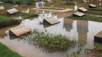 Penampakan salah satu makam yang terendam banjir di TPU Karet Bivak, Jakarta Pusat, Minggu (7/2/2021). [Suara.com/Alfian Winanto]