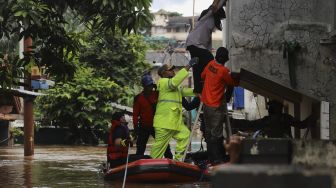 Petugas Pemadam Kebakaran bersama petugas Satpol PP menggunakan perahu karet mengevakuasi warga yang terjebak banjir di rumahnya di kawasan Pejaten Timur, Pasar Minggu, Jakarta, Senin (8/2/2021). [Suara.com/Angga Budhiyanto]