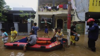 Sejumlah anak bermain di jalan yang tergenang banjir di kawasan Pejaten Timur, Pasar Minggu, Jakarta, Senin (8/2/2021). [Suara.com/Angga Budhiyanto]