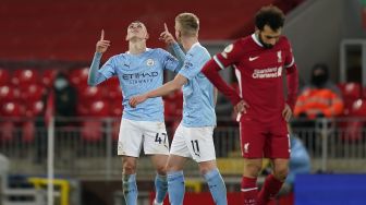 Gelandang Manchester City Phil Foden (kiri) melakukan selebrasi setelah mencetak gol keempat mereka selama selama pertandingan sepak bola Liga Premier Inggris antara Liverpool melawan Manchester City di Stadion Anfield, Liverpool, Inggris, Senin (8/2/2021) dini hari WIB. Tim Keeton / POOL / AFP
