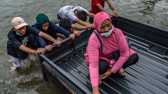 Sejumlah warga mendorong mobil mogok akibat menembus jalur Pantura Jalan Raya Kaligawe - Genuk yang terendam banjir di Genuk, Semarang, Jawa Tengah, Senin (8/2/2021). [ANTARA FOTO/Aji Styawan]