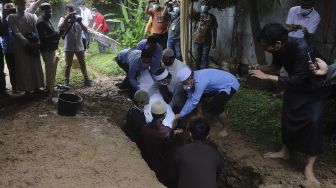 Kerabat dan keluarga memasukkan jenazah Ustadz Maaher At-Thuwailibi ke dalam pusara di Kompleks Pemakaman Pondok Pesantren Daarul Quran, Cipondoh, Tangerang, Banten, Selasa (9/2/2021). [Suara.com/Angga Budhiyanto]