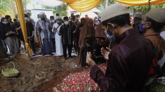 Kerabat dan keluarga memanjatkan doa di samping pusara Ustadz Maaher At-Thuwailibi di Kompleks Pemakaman Pondok Pesantren Daarul Quran, Cipondoh, Tangerang, Banten, Selasa (9/2/2021). [Suara.com/Angga Budhiyanto]