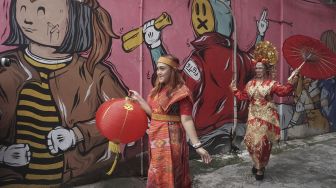 Warga yang mengenakan pakaian adat menyampaikan ucapan selamat Tahun Baru Imlek di jalan Gatot Subroto, Solo, Jawa Tengah, Rabu (10/2/2021). [ANTARA FOTO/Mohammad Ayudha]